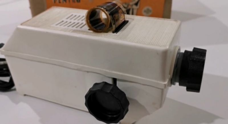 Un aparat de proiectat diafilme de colectie, cu rola de film pusa deasupra, exact genul de proiector vandut azi pe site-urile de anunturi
